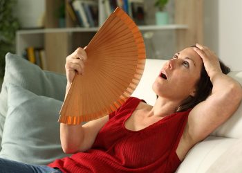 Adult woman fanning suffering hot flush